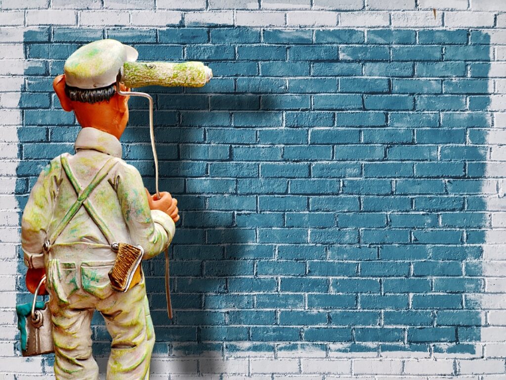 Wand malen – Maler steht vor einer Wand